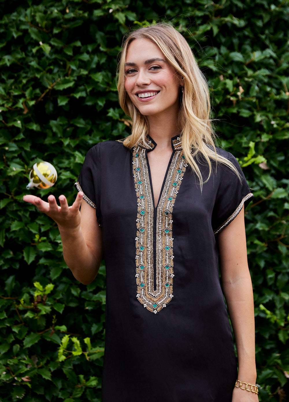 Hayden Caftan in Black, closer front view by a hedge