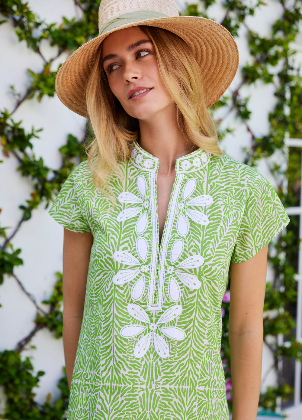 Lana Cap Sleeve Caftan in Coral Green, close-up of the neckline by a vine wall