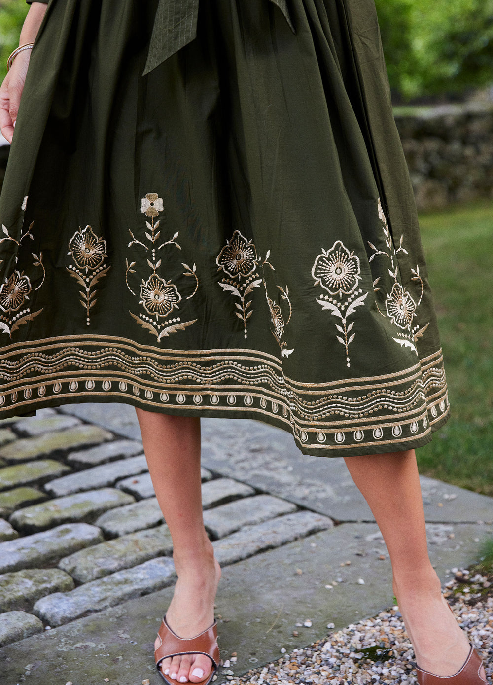 Elena Dress in Loden Green, close-up of the hem on a stone path