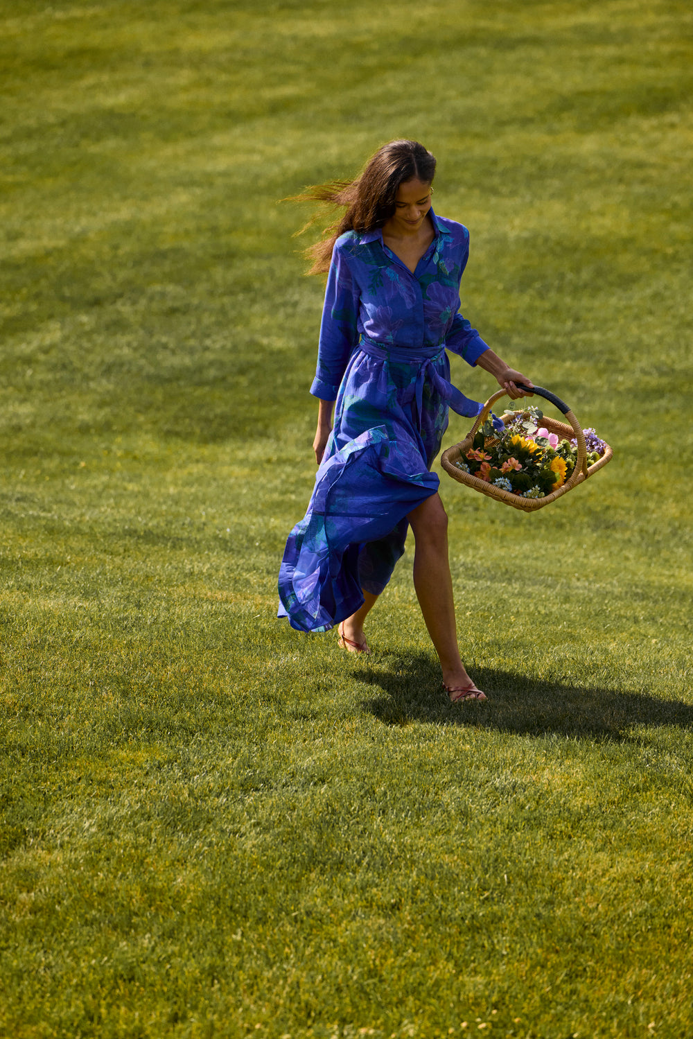 Kit Shirtdress in Helin Royal, walking on a lawn with a flower basket
