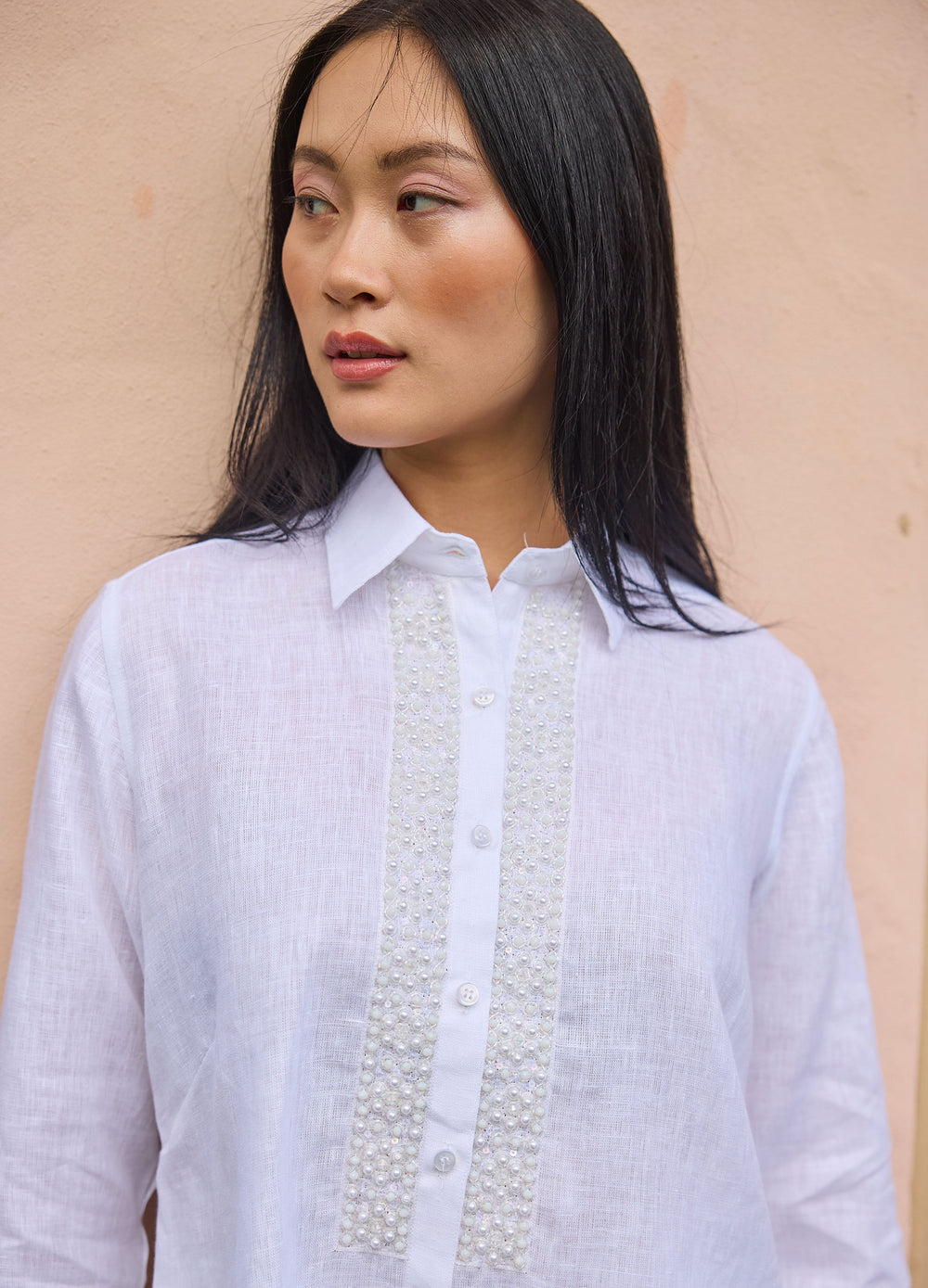 Pearl Flower Shirt in White, closer view by a wall, looking aside