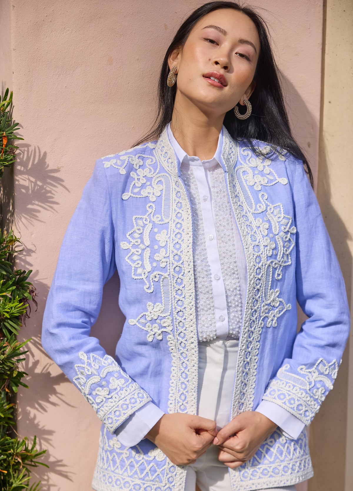Ceci Jacket in Blue, front view by a garden wall